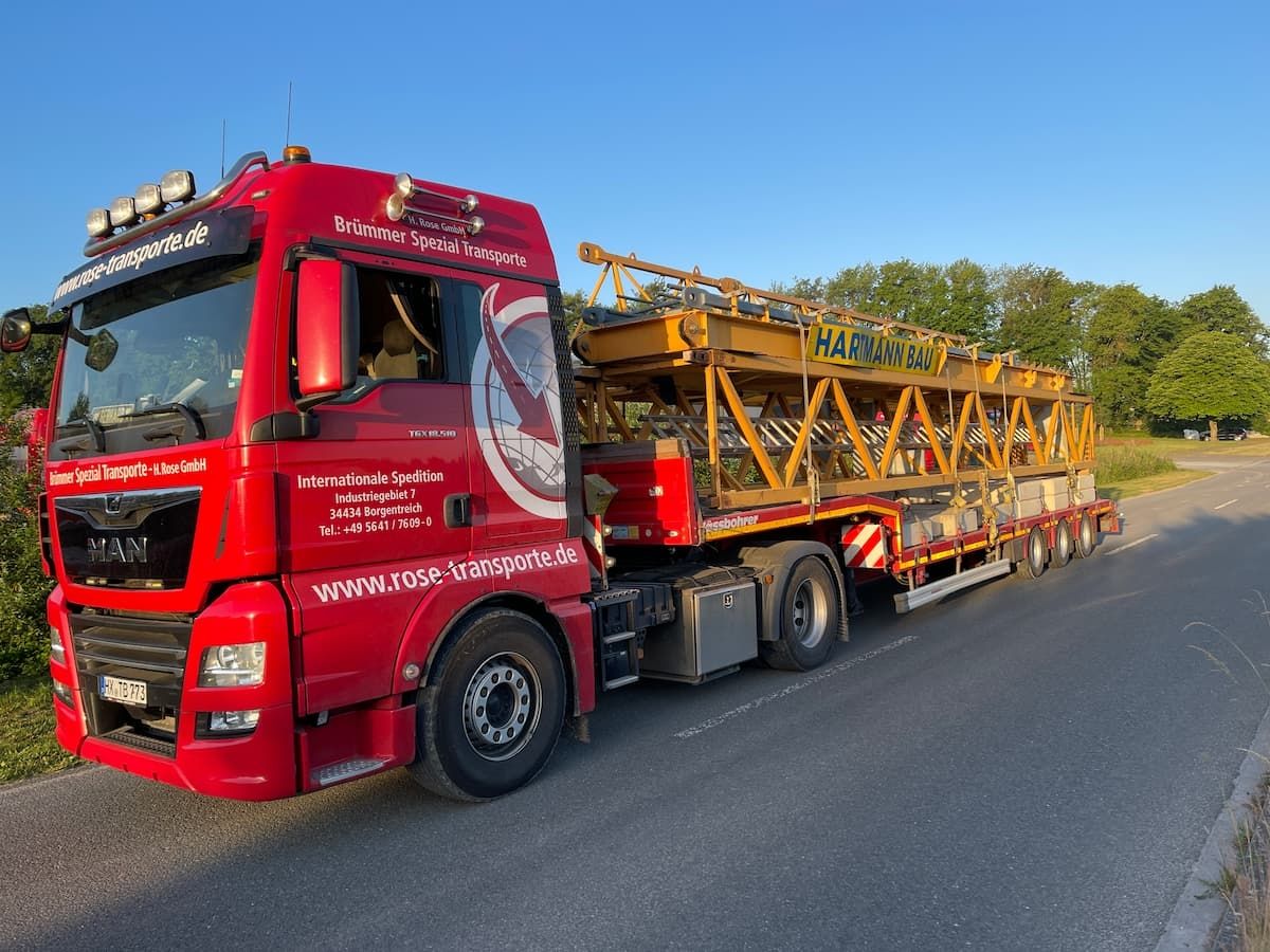 Roter Transporter mit Baumaschine beladen